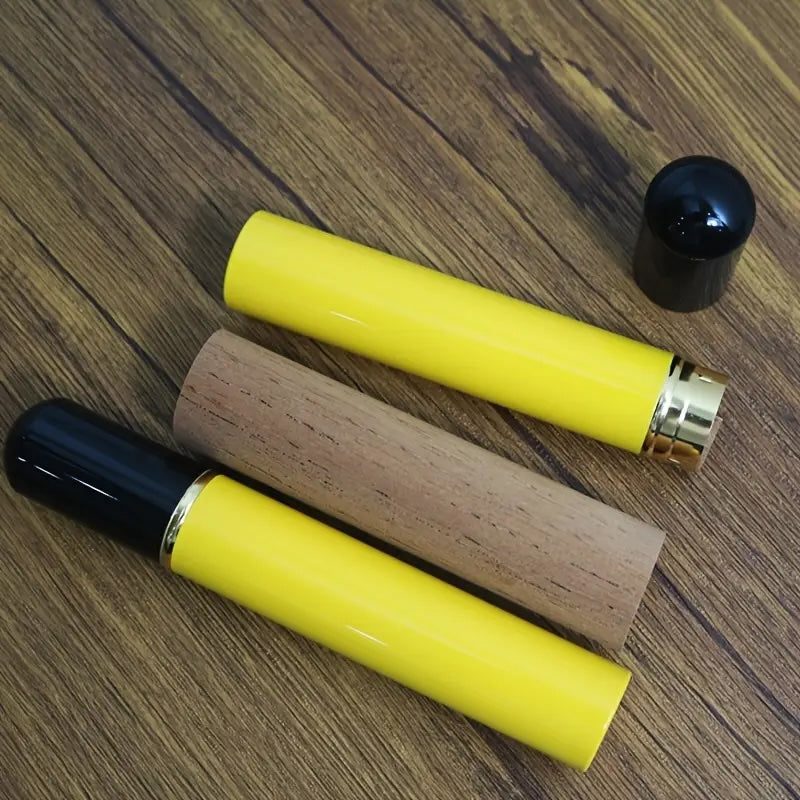 Two yellow lip balm tubes with black caps on a wooden surface