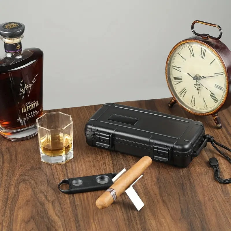 Bottle of La Fourchette whiskey, glass, black travel case, cigar, and lighter on a wooden surface with a clock in the background.