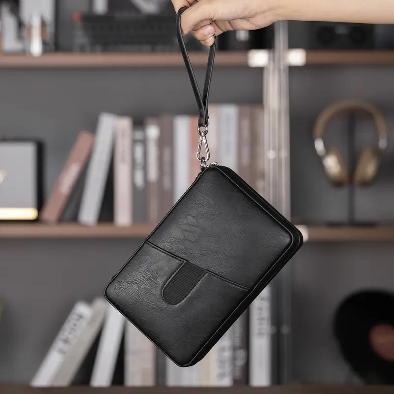 Black leather pouch held by a hand with a blurred bookshelf background